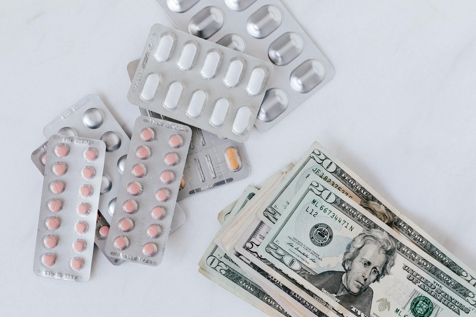 different pill blisters near pile of american dollar banknotes